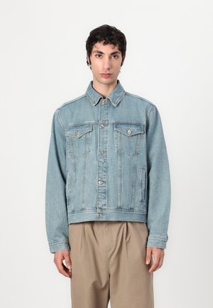 Light blue denim jacket with a collared neck, front chest pockets, and button closure. Features distressed texture and shoulder seams.