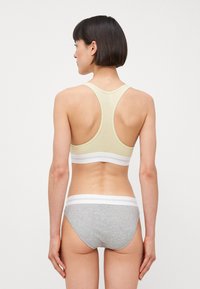 Lys gul ribbet sportsbh med racerback-design og hvit elastisk band, kombinert med grå ribbet truse med hvit livlinning.
