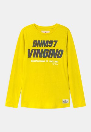 Gul langærmet skjorte med "DNM97 VINGINO Manufacturing Co. Since 2001" trykt i sort og hvid på forsiden.