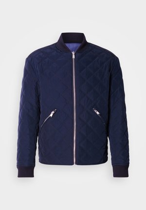 Mornarska prošivena bomber jakna s prednjim patentnim zatvaračem, dva džepa sa strane na patentni zatvarač i plićim rukavima i ovratnikom. Glatka tekstura s uzorkom rombova.