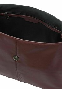 Sac en cuir marron avec fermeture à pression magnétique, intérieur en tissu noir et poche intérieure zippée.