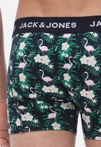 Boxeri negri cu un model tropical cu flamingo roz și flori albe pe un fundal de frunziș verde închis. Talie elastică etichetată.