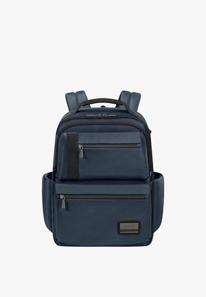 Sac à dos bleu marine avec plusieurs compartiments zippés, bretelles rembourrées, poches latérales et poignée supérieure sur fond blanc.