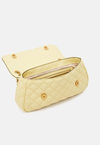Pikowana żółta torebka z eko-skóry z złotymi okuciami, zamknięciem na klapę od góry oraz wewnętrznymi przegródkami do organizacji.