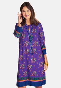 Lila Kleid mit runden Blumenmustern, Dreiviertelärmeln und einem Schlüssel-Ausschnitt. Verfügt über bunte Akzente und hat einen geraden Schnitt.