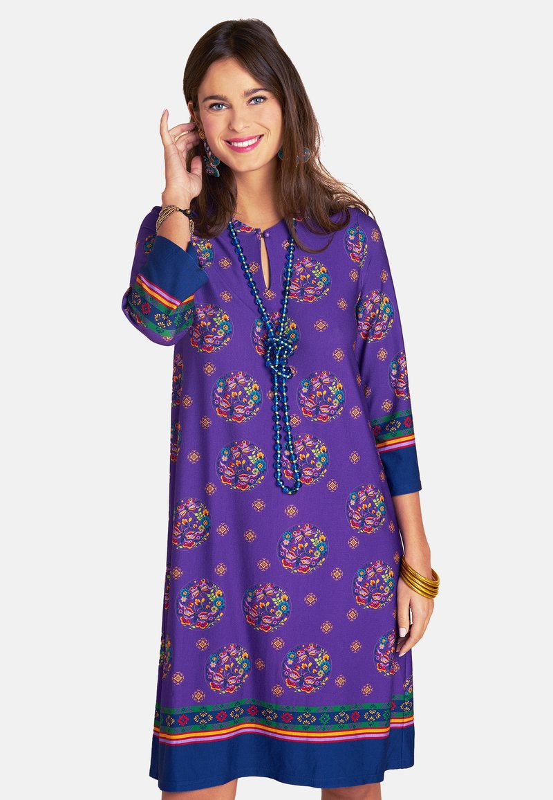 Lila Kleid mit runden Blumenmustern, Dreiviertelärmeln und einem Schlüssel-Ausschnitt. Verfügt über bunte Akzente und hat einen geraden Schnitt.