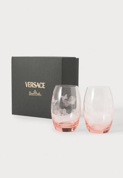 Deux verres à boire teintés de rose, dont un avec des gravures de papillons, à côté d’une boîte noire de marque Versace Rosenthal sur fond blanc.