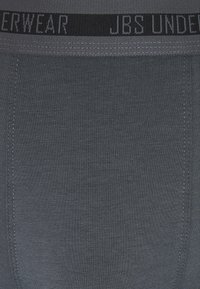 Ropa interior gris de algodón con una textura suave, con una cinturilla elástica negra que presenta el texto "JBS UNDERWEAR" en gris. Diseño sin costuras.