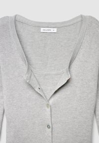 Grauer Cardigan mit V-Ausschnitt, gerippter Struktur und vier Knöpfen. Hergestellt aus weichem Material. Das Etikett trägt die Aufschrift "CALLIOPE S."