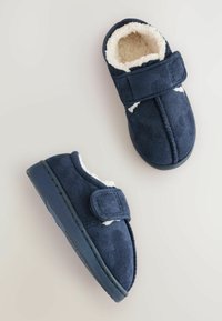 Pantofole blu navy con un morbido rivestimento in pile, fascia in velcro e suola piatta in gomma, caratterizzate da una superficie testurizzata e forma arrotondata.