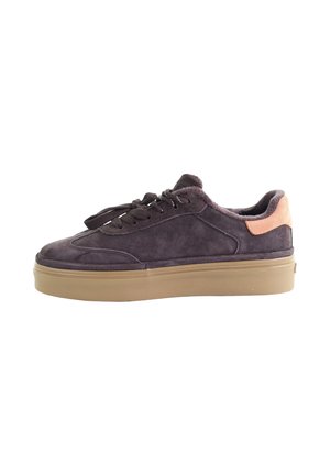 Ciemnobrązowy zamszowy sneaker z beżową podeszwą i jasnobrązową łatką na pięcie, wyposażony w sznurowadła i wyściełany kołnierz.