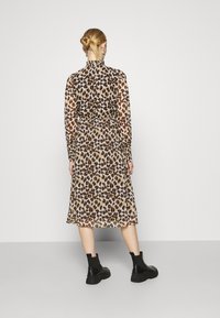 Midi šaty s leopardím potiskem, dlouhými rukávy, průhlednou tkaninou, vysokým límcem a elastickým pasem. kombinováno s černými kotníkovými botami.