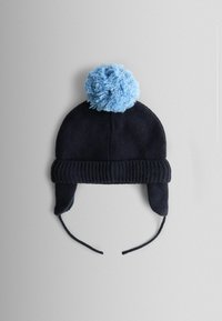 Tumesinine kootud müts hele sinise pompomiga, kõrvaklapid ja lõualikud, soonikuga äär, mis tagab kindla sobivuse.