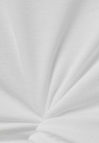 Hvidt stof med en blød, tekstureret overflade, der udviser et snoet mønster. Materialet virker let og en smule gennemsigtigt.