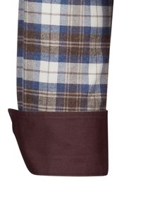 Camicia di cotone a quadri con motivi a check blu, bianchi e marroni. Il polsino marrone scuro, dalla texture liscia, contrasta con il tessuto a motivi.