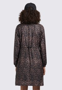 Giacca in stampa leopardata nera e marrone con maniche lunghe, polsini elastici e vita regolabile con coulisse. Tessuto liscio e leggero.