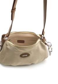 Bolso de tela beige con cierre de cremallera, detalles en cuero marrón y asa trenzada blanca y roja. El interior muestra un forro liso y un bolsillo.