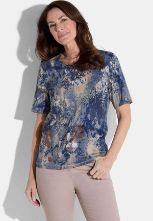 Haut à manches courtes bleu à motifs floraux dans un motif mixte avec des teintes de bleu, marron et beige. Tissu doux avec un col rond.