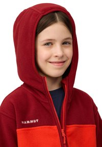 Bordeaux-rot und leuchtend orange Fleece-Hoodie mit Reißverschluss, ausgestattet mit einer großen Kapuze und dem "MAMMUT"-Logo auf der Brust. Weicher Stoff, enganliegende Passform.