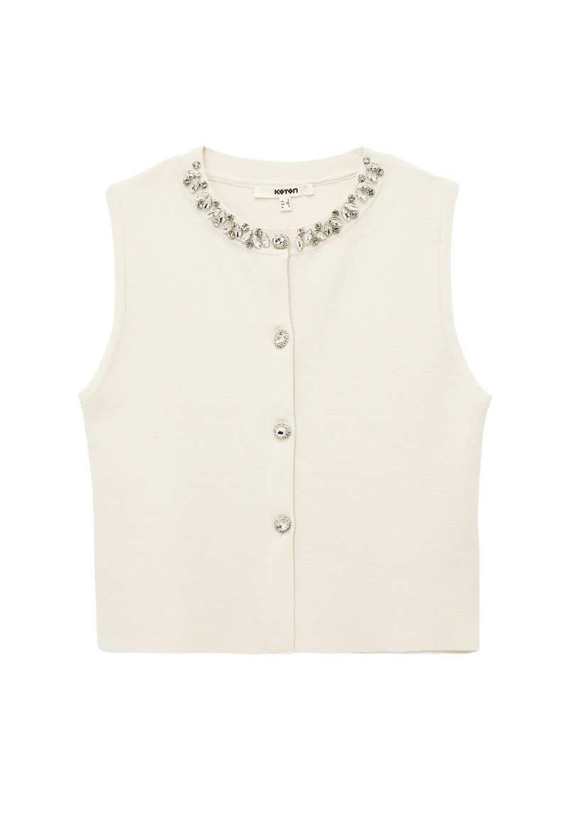 Crèmekleurig mouwloos topje met een ronde hals, versierd met een decoratieve kristallen halslijn en knoopsluitingen aan de voorkant. Zachte gebreide textuur.