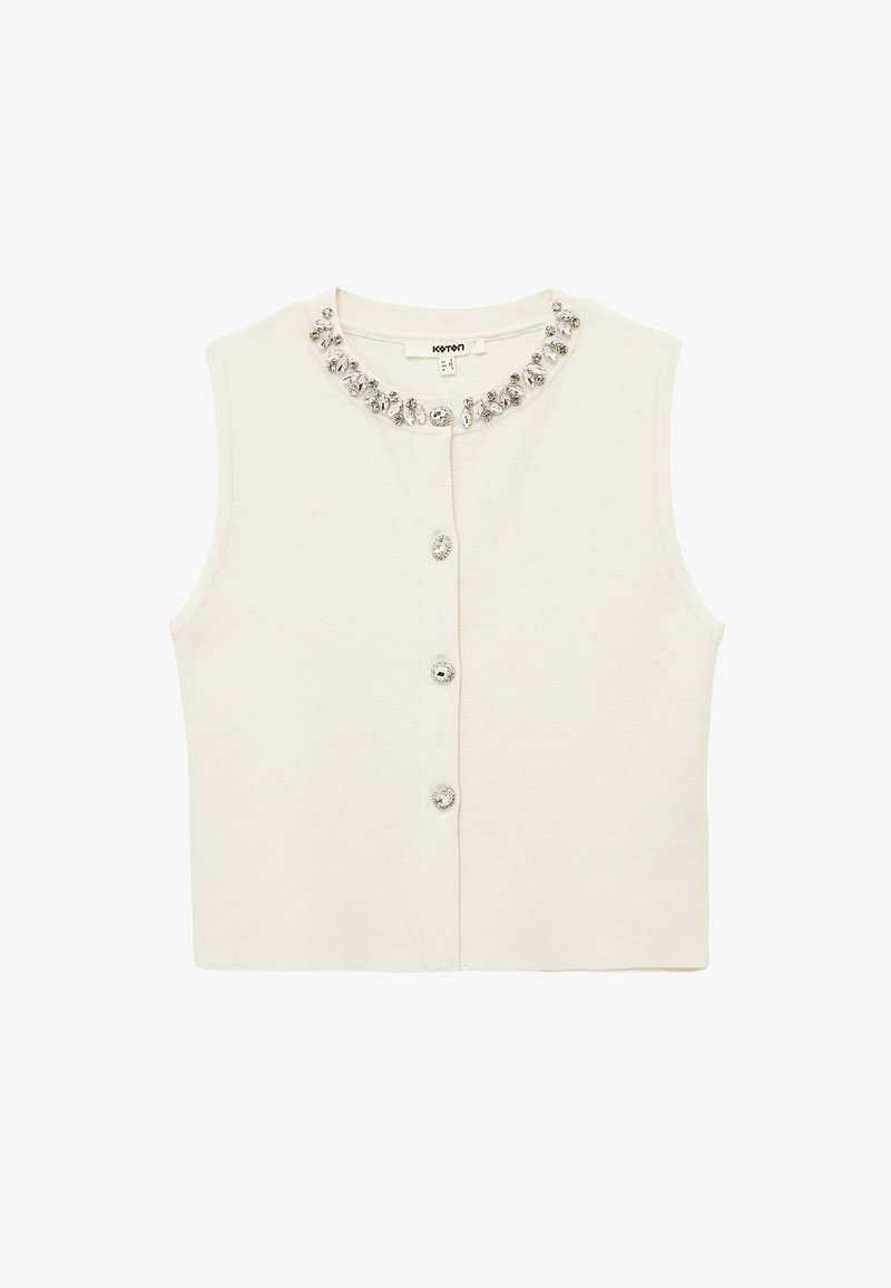 Crèmekleurig mouwloos topje met een ronde hals, versierd met een decoratieve kristallen halslijn en knoopsluitingen aan de voorkant. Zachte gebreide textuur.