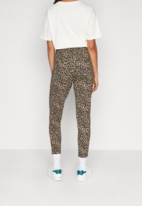 Lepardmönstrade leggings i ett elastiskt material, med hög midja och figurnära silhuett, matchat med vita sneakers och hörsockar.