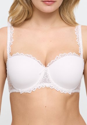 Witte gewatteerde beha met kanten rand en bloemrijke borduursels, gedragen door een vrouw met blond haar, die de halslijn en bovenlichaam toont.