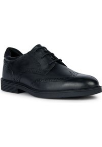 Svart läder oxford-sko med rund tå, snörning, brogue-detaljer och en texturerad gummisula. Slät yta med subtil glans.
