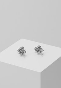 Silverstiftörhängen med blommönster, med detaljerad gravyr och polerade ytor. Positionerade på en ren, vit display.