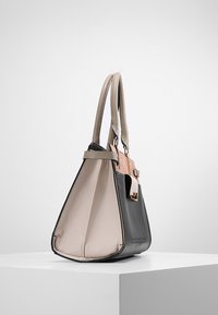 Leather handbag with a triangular shape, featuring a black bottom, beige body, and a pink accent with gold hardware on the handle.