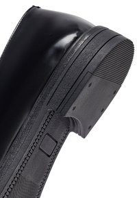 Stivaletto in pelle nera con punta rotonda, suola in gomma testurizzata e finitura liscia, dotato di tacco rinforzato per una maggiore durabilità.