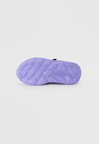 Semelle de chaussure en caoutchouc violet avec des motifs texturés, présentant des formes de traction multidirectionnelles pour une meilleure adhérence et stabilité.