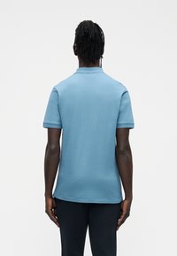 Polo azul de manga curta feito de algodão macio, com colarinho clássico e detalhes canelados contrastantes nas mangas.