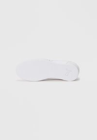 White sneaker sole with textured rubber, solid design, slight curve at the heel, and minimalist logo detail on the side.