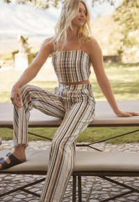 Ensemble deux pièces comprenant un haut court et un pantalon taille haute en rayures verticales de beige, marron et olive. Tissu léger, coupe décontractée.