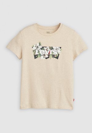 Beige t-skjorte med korte ermer og et blomsterdesign med magnolias og teksten "Levi's" i hvit mot en svart bakgrunn.