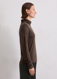 Bruine coltrui gemaakt van een zachte stof, met lange mouwen en een aansluitend design, gecombineerd met een donkere rok.