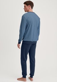 Blauw gestreepte lange mouwen top met een ronde halslijn en bijpassende donkerblauwe broek. Beide stukken zijn gemaakt van een zachte, ademende stof.
