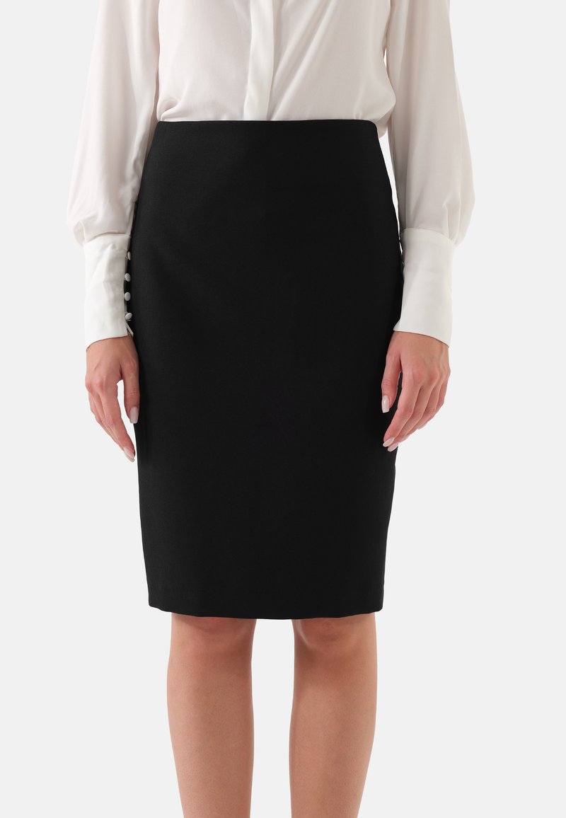 Zwarte kokerrok met een gladde textuur en een getailleerde silhoeet. Voorzien van decoratieve knopen aan de zijkant, gecombineerd met een witte blouse.
