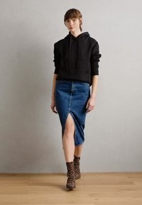 Haut à capuche noir, jupe en denim avec fente avant, bottines à imprimé léopard marron. Design simple, texture douce, look décontracté.