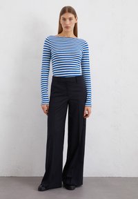 Blue and white striped long-sleeve top paired with tailored black wide-leg pants. Smooth fabric, minimalistic design, no visible patterns or logos.