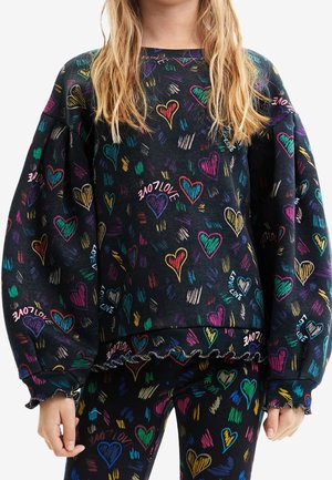 Enfant portant un sweat-shirt et un pantalon noirs ornés de motifs de cœurs colorés et du texte "LOVE" en plusieurs couleurs vives.