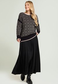 Czarny sweter dzianinowy z diamentowym wzorem i ściągaczem, zestawiony z plisowaną czarną spódnicą i masywnymi czarnymi botkami. Teksturowana tkanina.