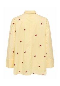 Chemise jaune à manches longues, col à revers, avec broderies rouges de fraises éparses. Dos uni, confectionnée en tissu léger.