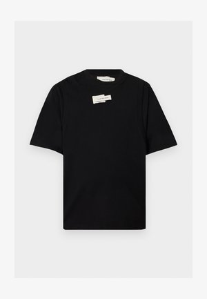 Sort T-shirt med korte ærmer og rund halsudskæring med to små hvide rektangulære mærkater nær halslinningen, forfra på ensfarvet baggrund.