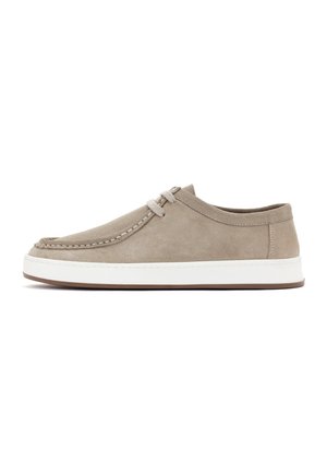 Botte en suede beige avec un bout arrondi, des coutures contrastées et une semelle en caoutchouc blanche. Présente un design à lacets avec des lacets gris discrets.