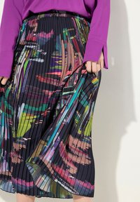 Jupe plissée multicolore avec une base sombre et des motifs abstraits vifs en rose, vert et bleu. Taille élastique et tissu léger.