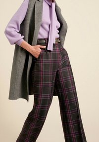 Šedá vesta přes fialkový žebrovaný svetr s mašlí. Široké kárované kalhoty v tmavých tónech s fialovými a modrými akcenty. Design s hladkým předním dílem.