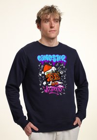 Námořnická mikina má grafický design s karikaturní postavou, která drží boombox. Obsahuje barevný text "GANGSTER WRAPPER." Hladká textura.