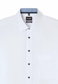 Weißes Hemd mit schwarzen Knöpfen, einem blauen gemusterten Innenkragen und einer einzelnen Brusttasche. Der Stoff wirkt glatt und leicht.